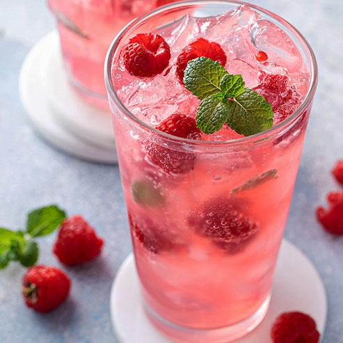 Glass of non-alcoholic fruit punch with raspberries and ice, garnished with mint