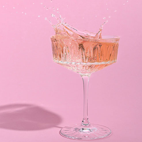 Glass of moscato against a pink wall
