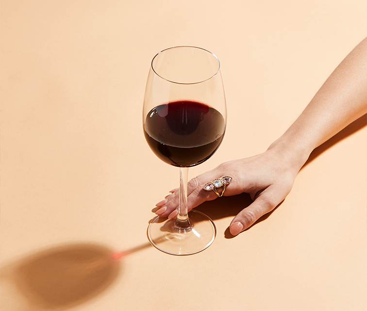 female hand holding red wine glass